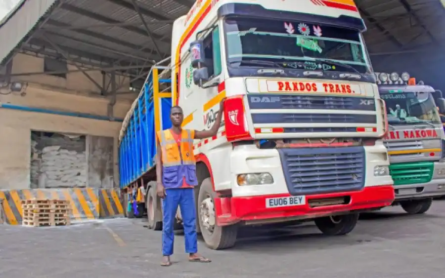 A dock worker standing beside a truck at a warehouse loading bay