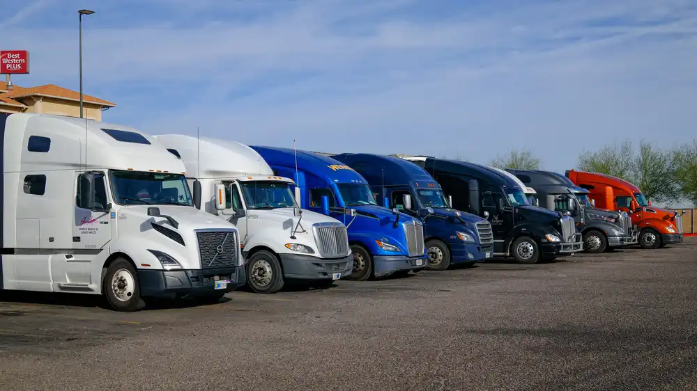 A row of trucks parked at a truck stop, waiting for their next dispatch